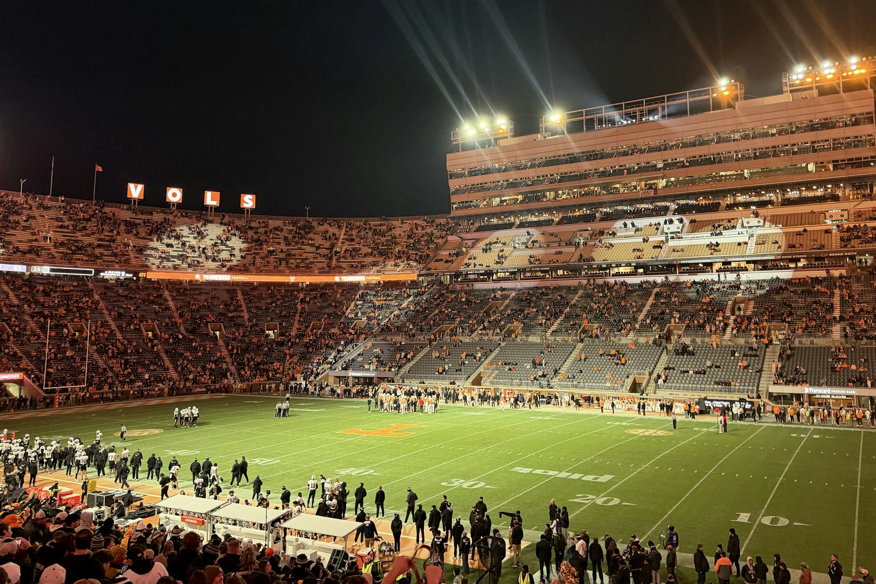 A packed football stadium under the lights